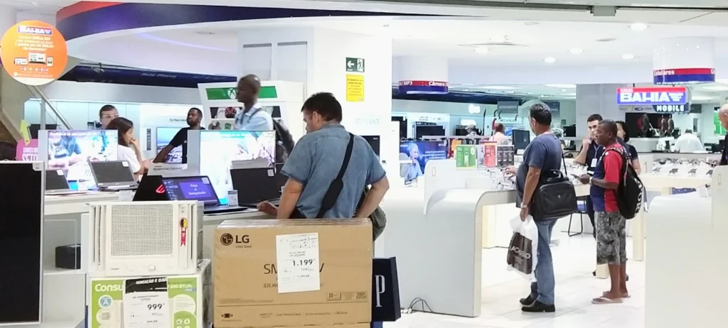 várias pessoas em uma loja olhando eletrodomésticos.