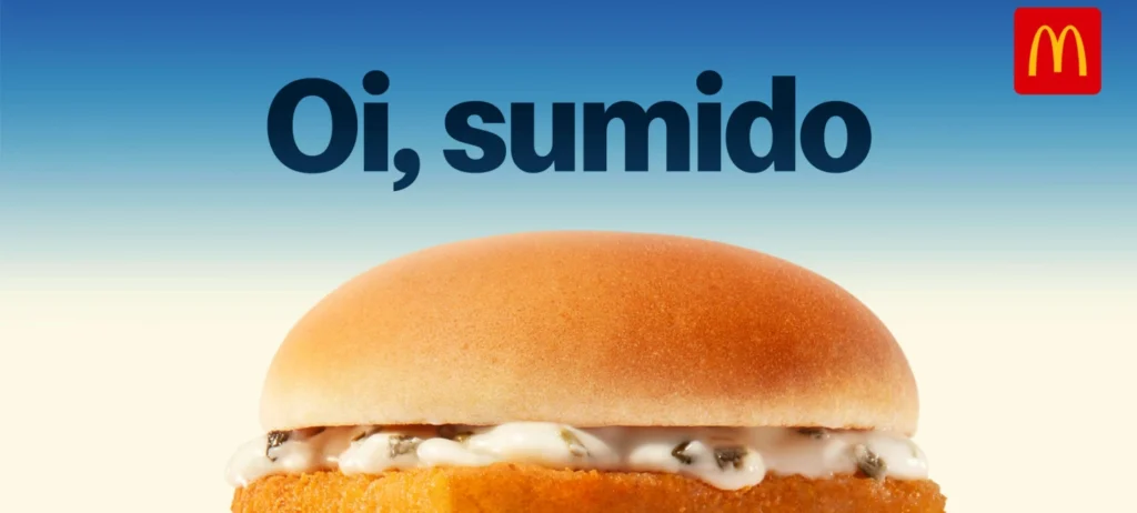 Metade de cima do sanduíche McFish pode ser vista. A frase "Oi, sumido' está em preto acima do lanche. No canto direito superior, está a logo do McDonald's em vermelho e amarelo. O fundo é azul e branco.