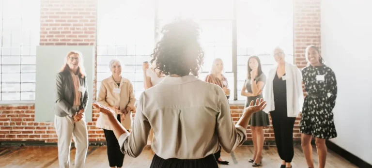Uma mulher que está de costas conversa com outras mulheres, que estão de frente para a líder.