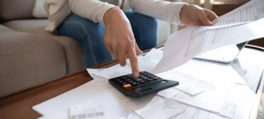 Uma pessoa digita em uma calculadora enquanto segura e lê um bloco de documentos.