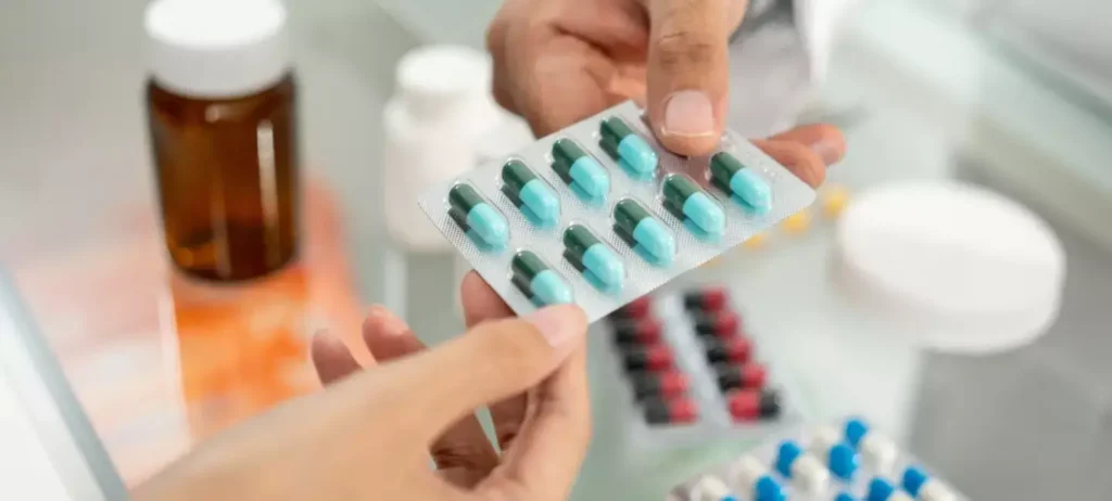 Duas pessoas seguram uma cartela de remédios.