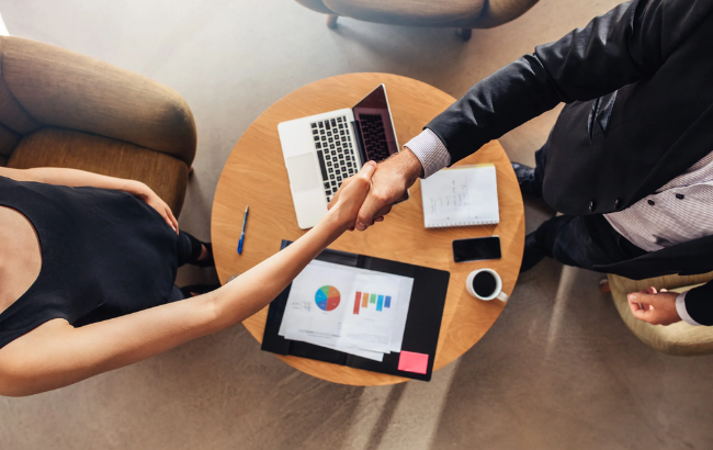 Homem e mulher em aperto de mão no ambiente de negócios.